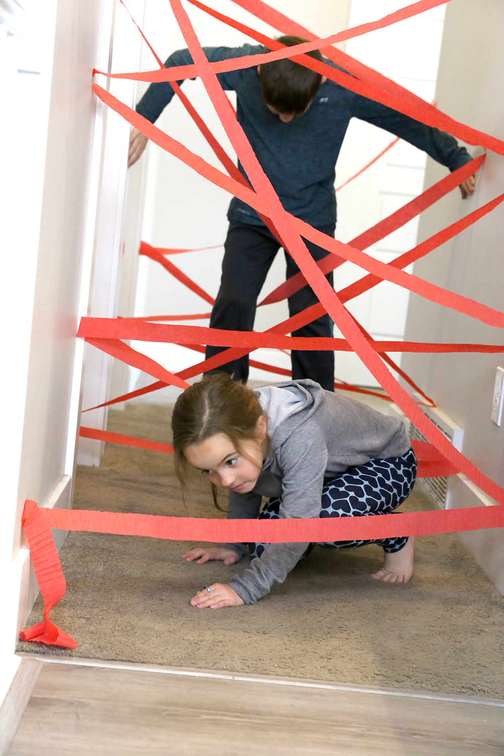 Kids making their way through hallway crisscrossed by crepe paper to make a laser maze