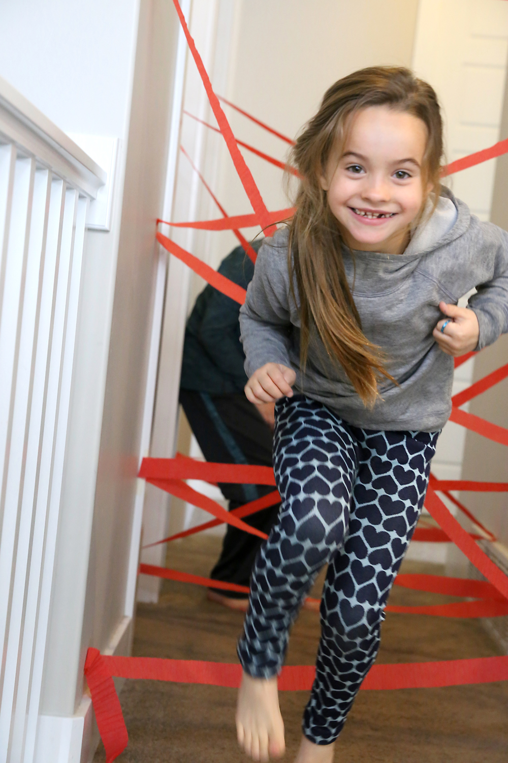 Kids making their way through hallway crisscrossed by crepe paper to make a laser maze