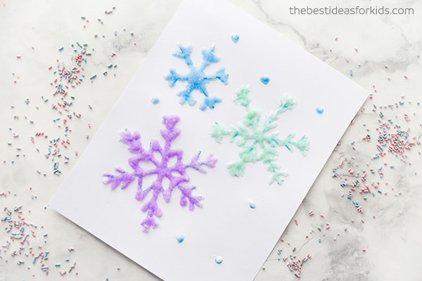 Paper with snowflakes drawn in glue, covered in salt, and painted different colors