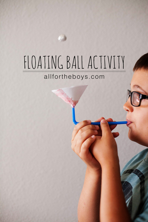 A boy blowing through a straw to make a small ball float