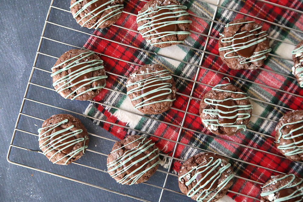 Chocolate cookies with melted mint truffle and mint drizzle on a cooling rack