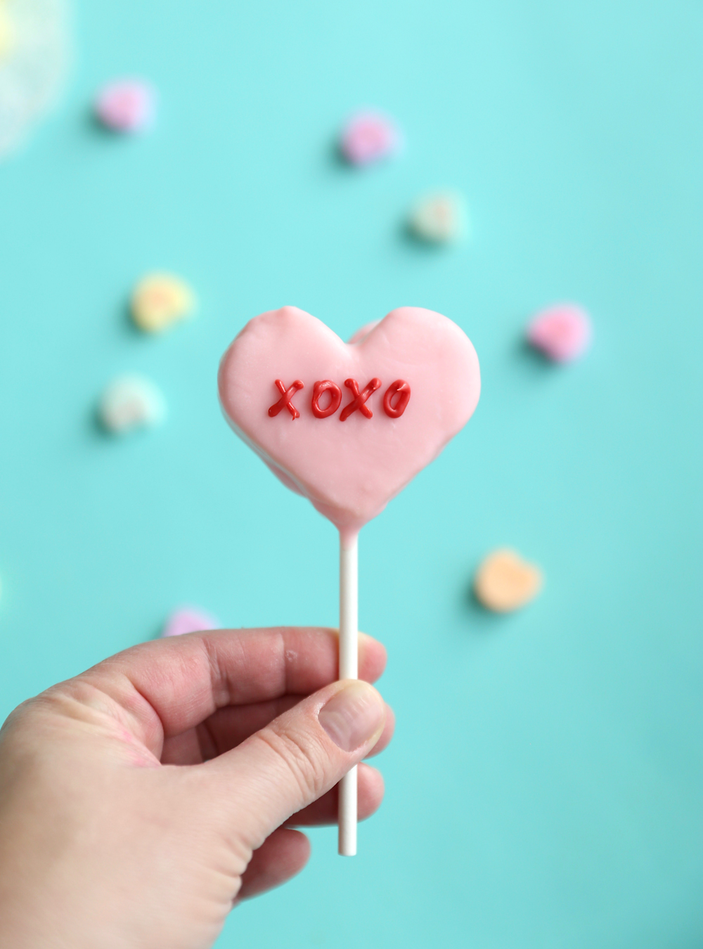 Hand holding conversation heart cake pop