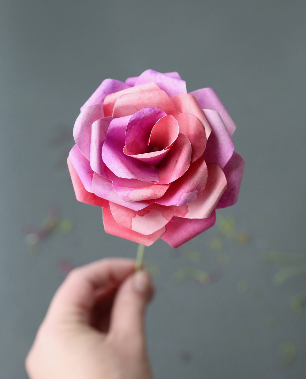 Hand holding a pink rose made from paper