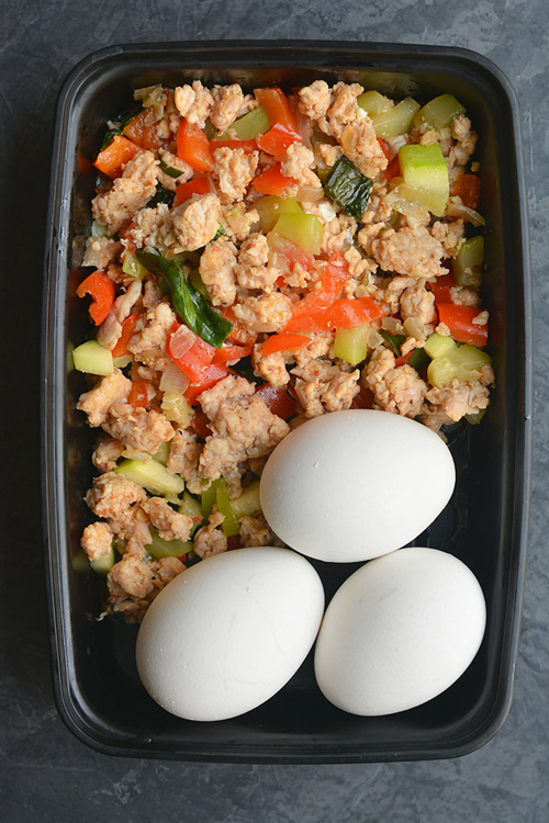 A plastic container filled with vegetable hash with eggs