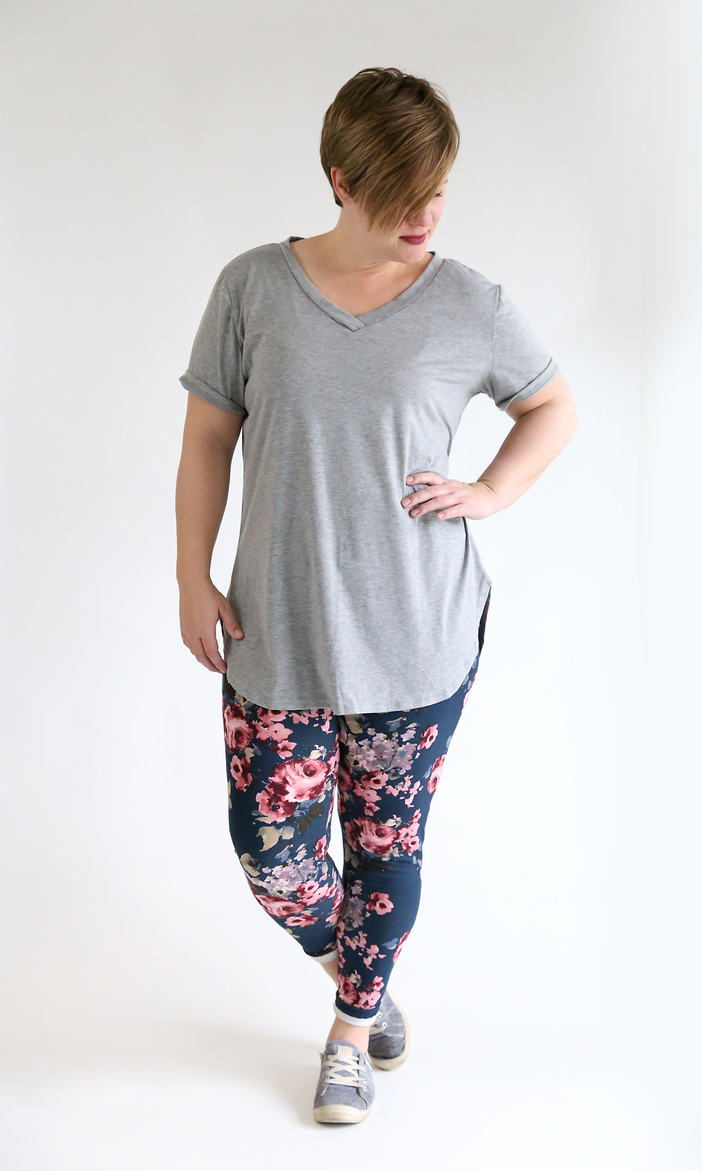 A woman wearing a long grey t-shirt and floral leggings