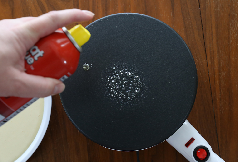 Spraying nonstick spray on crepe maker
