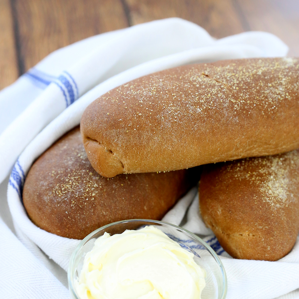 Small loaves of sweet brown bread on a towel with butter