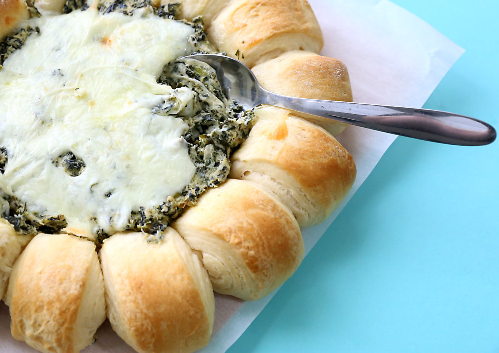 Spinach dip surrounded by bread rolls