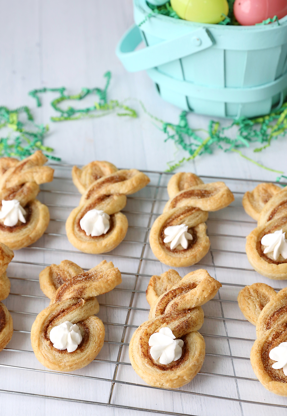 Cinnamon sugar bunny treats made from twisted strips of puff pastry with dots of whipped cream for tails