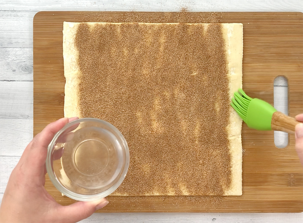Adding cinnamon sugar over the butter on a pastry sheet