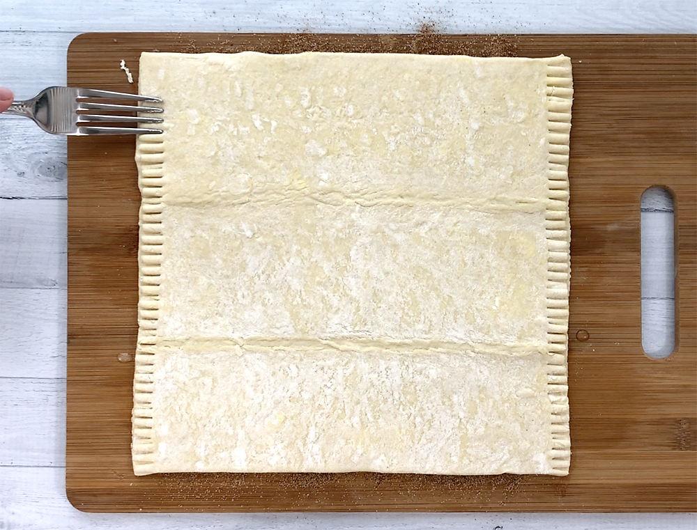 Using a fork to crimp the edges of the pastry sheet