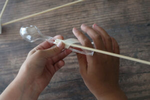 Taping plastic spoon to the end of a skewer