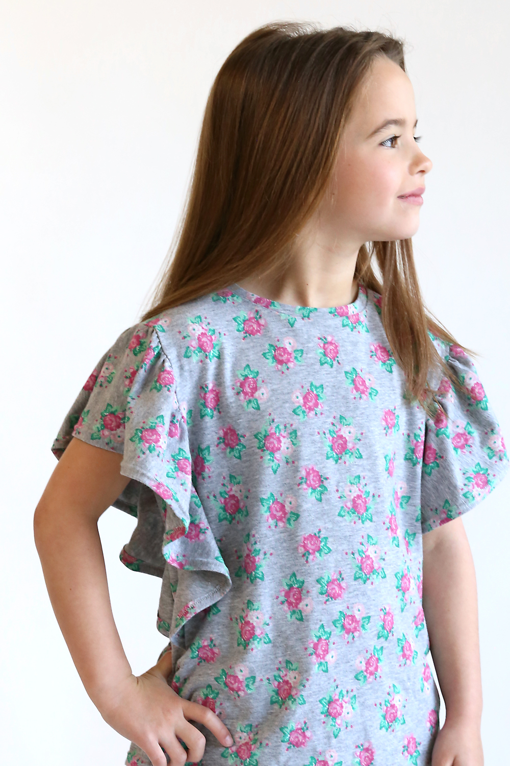 A little girl wearing a floral top with wavy sleeves