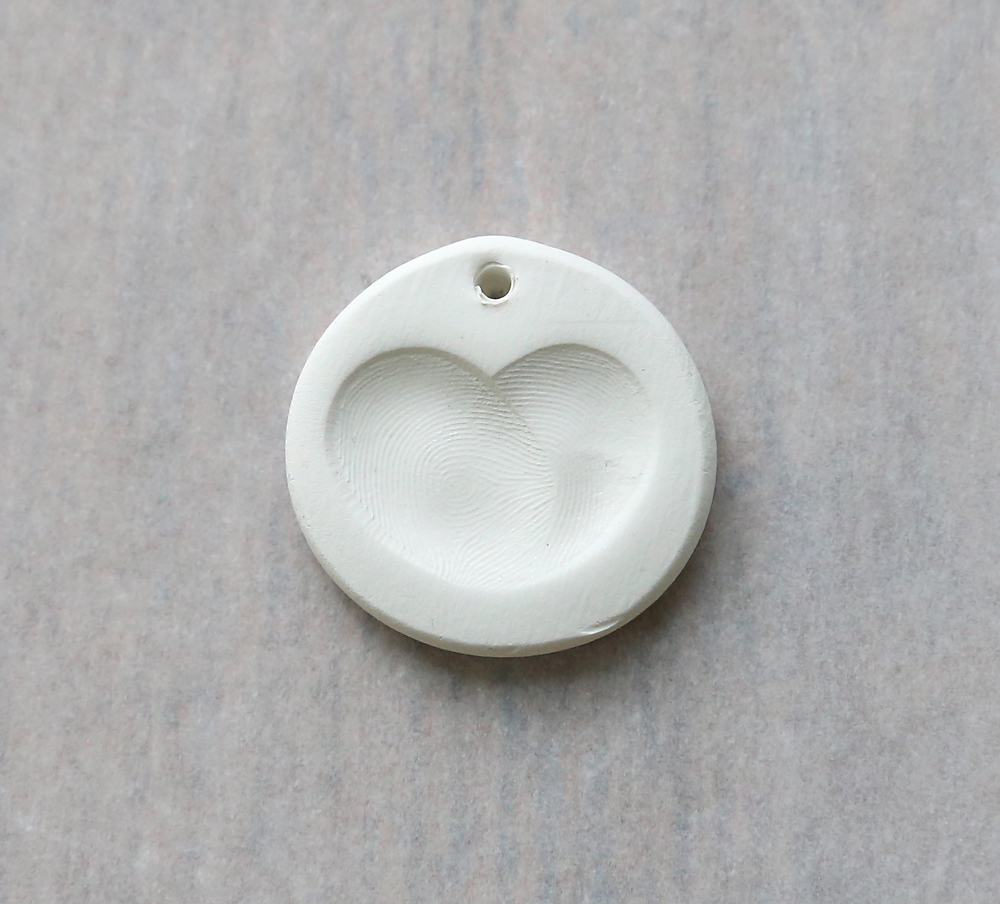 A clay pendant with a fingerprint heart