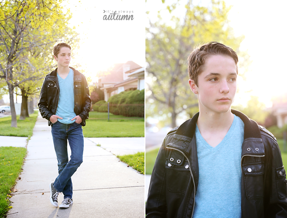 A boy in a leather jacket standing with on foot crossed in front of the other