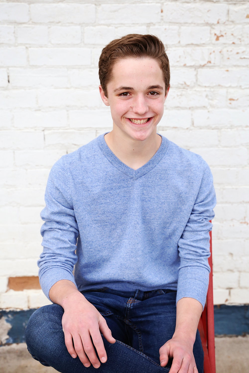 Poses for boys - teen boy sitting on a chair with one foot crossed on the other knee