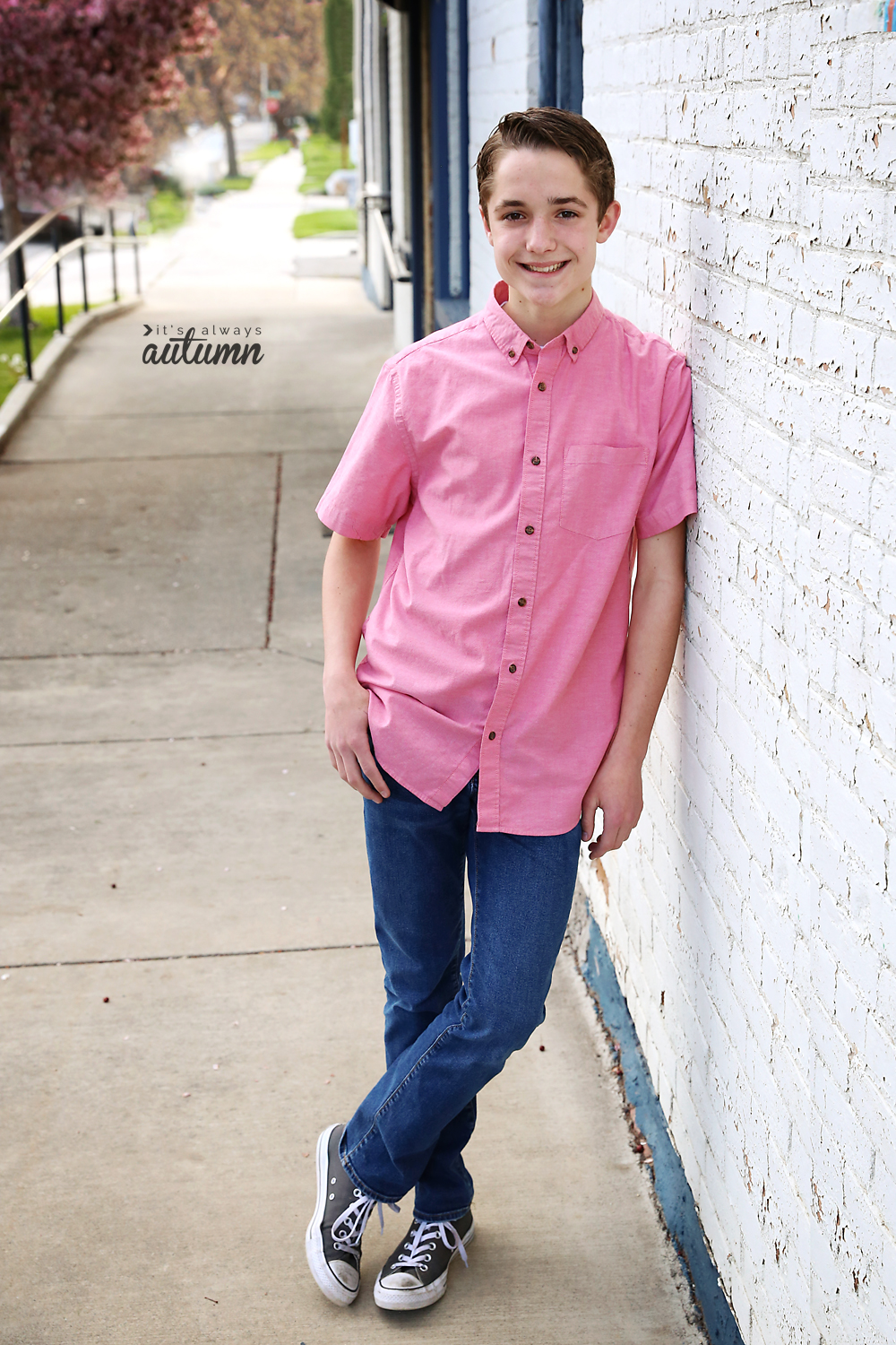 A boy posing against a white brick wall