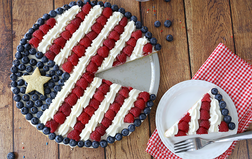 An American flag fruit pizza with one slice cut out on a plate