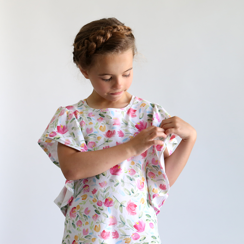 A little girl wearing a floral dress looking at the flutter sleeve
