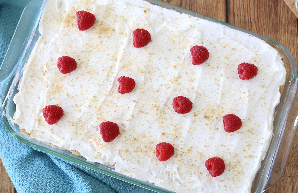 a 9x13 pan full of raspberry cheesecake icebox cake with raspberries on top