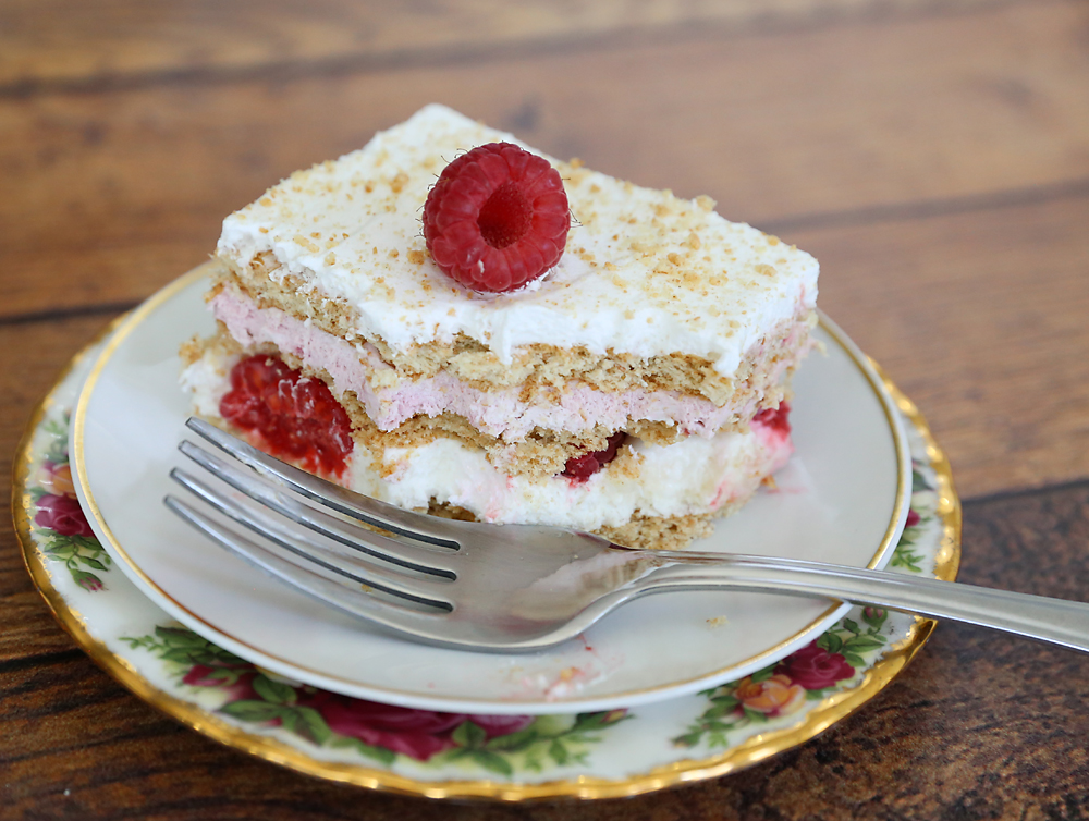A slice of raspberry cheesecake icebox cake on a plate with a fork