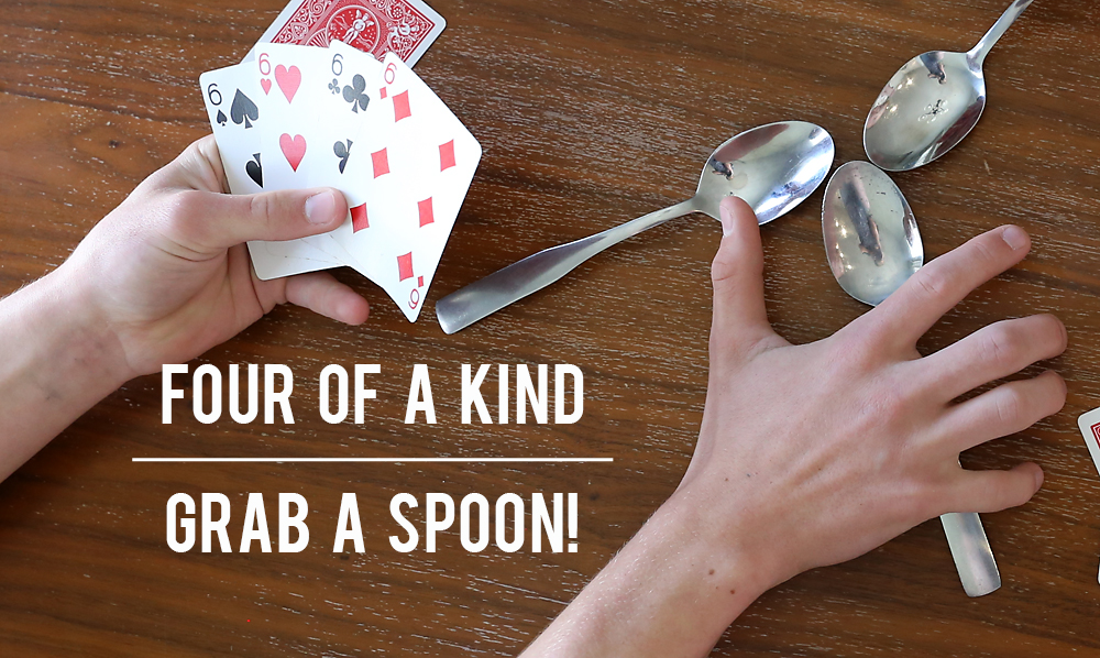 Hands holding playing cards and grabbing a spoon