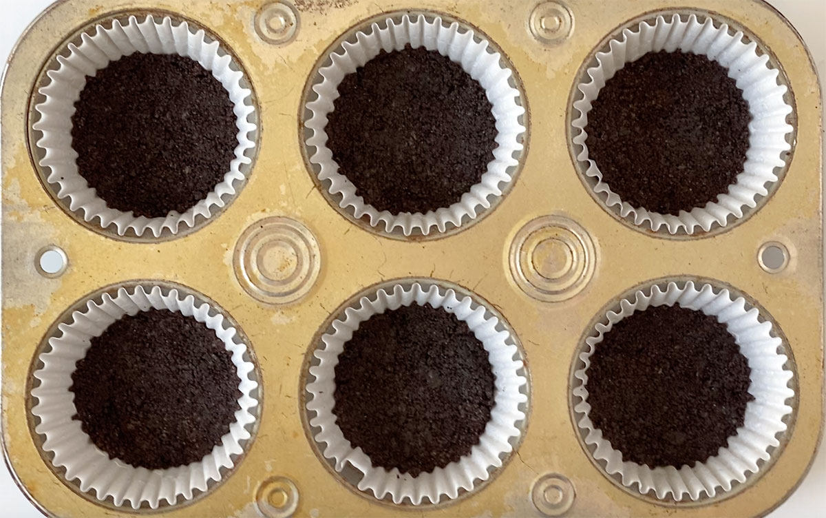 How to make Oreo ice cream sandwiches: press Oreo crumbs in the bottom of cupcake tin