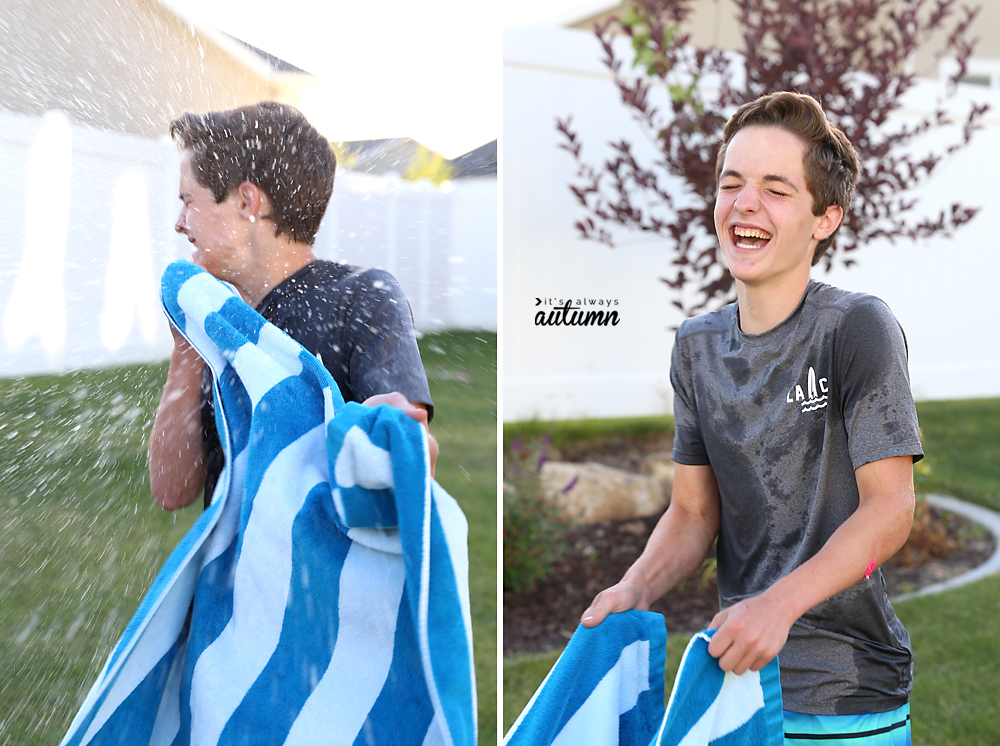 Boy holding a beach towel getting hit by a water balloon