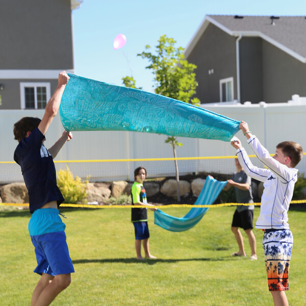 Kids playing water balloon volleyball using towels to toss water balloons
