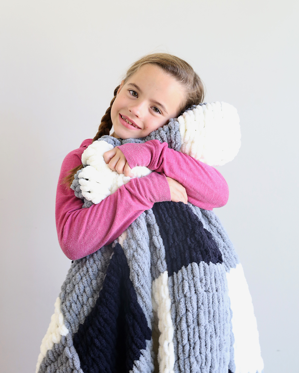 Girl snuggling with a finger knit blanket made from loop yarn