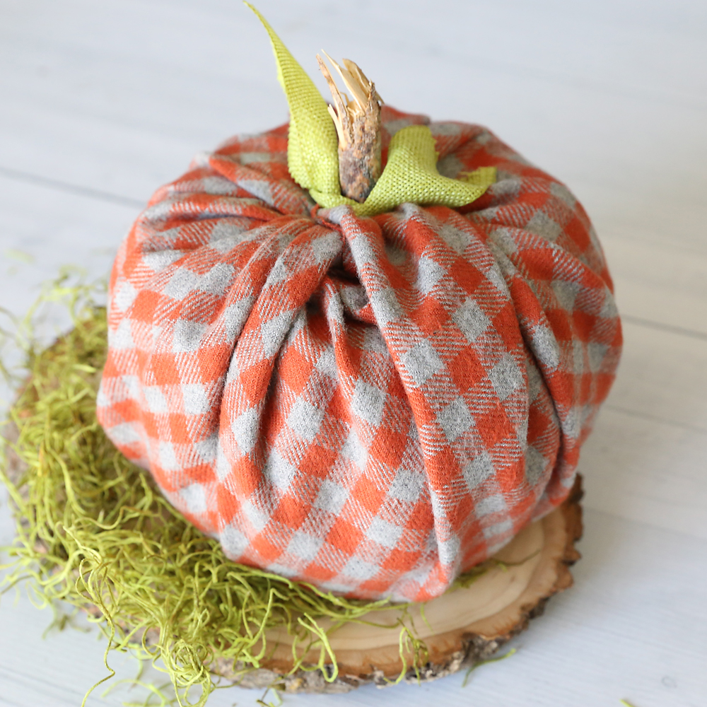 Pumpkin made from a roll of toilet paper wrapped with flannel fabric with a stick for the stem and ribbon tied around for leaves
