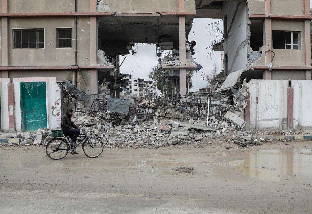 Person on a bicycle in front of a ruined building