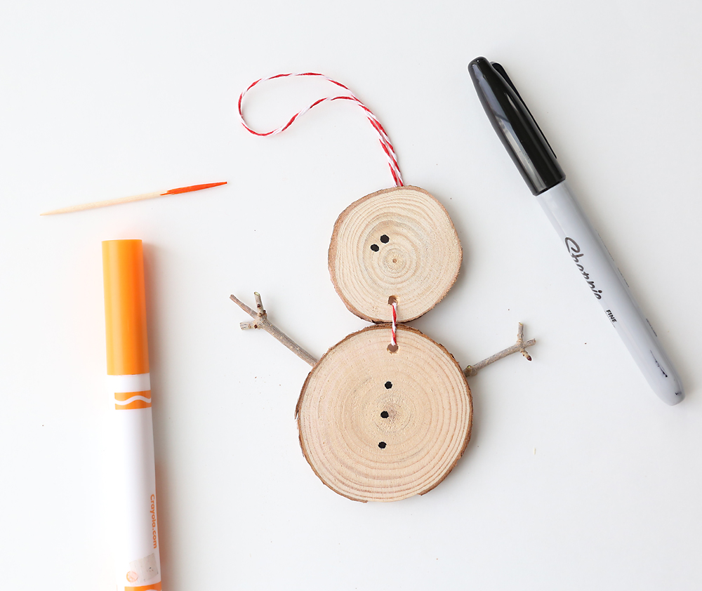 Wood slice snowman with dots for eyes and toothpick end colored orange