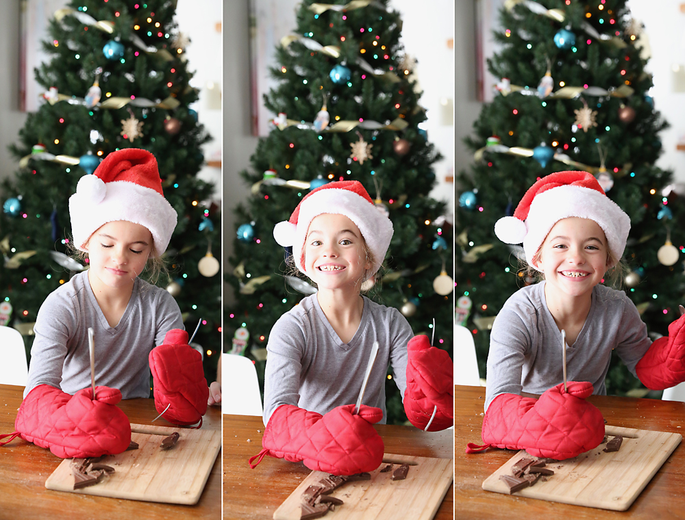 Girl in Santa hat and oven mitts cutting chocolate bar with a fork and knife