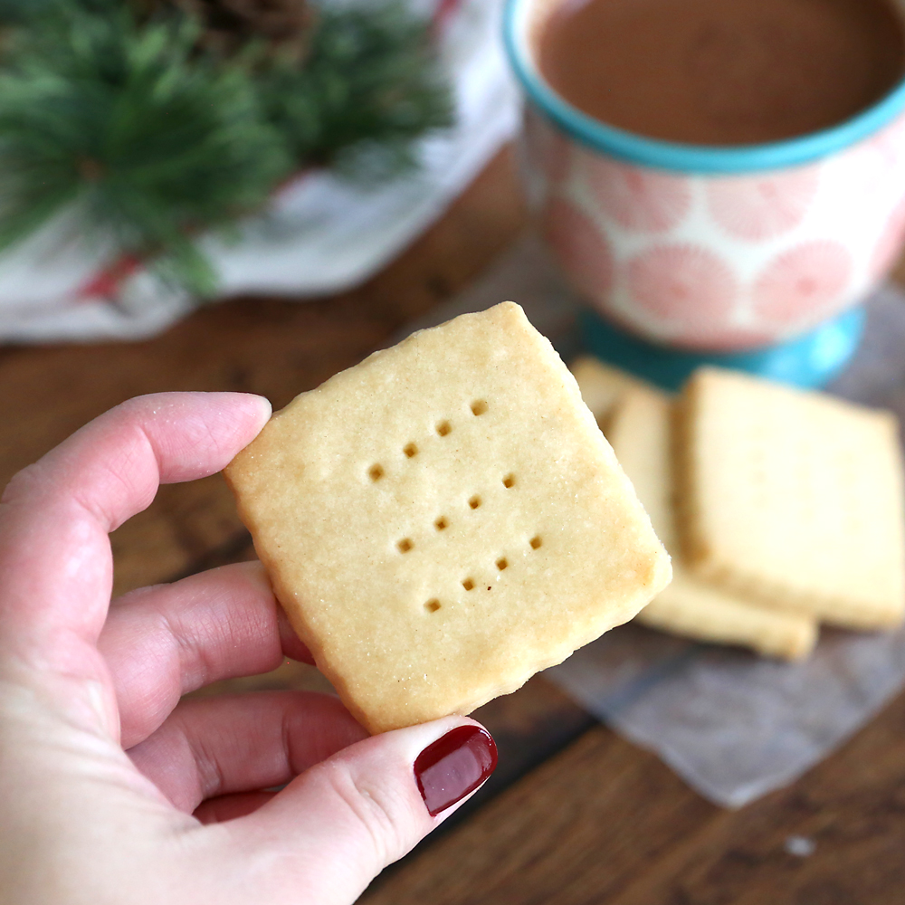 Hand holding a shortbread cookie, with cocoa