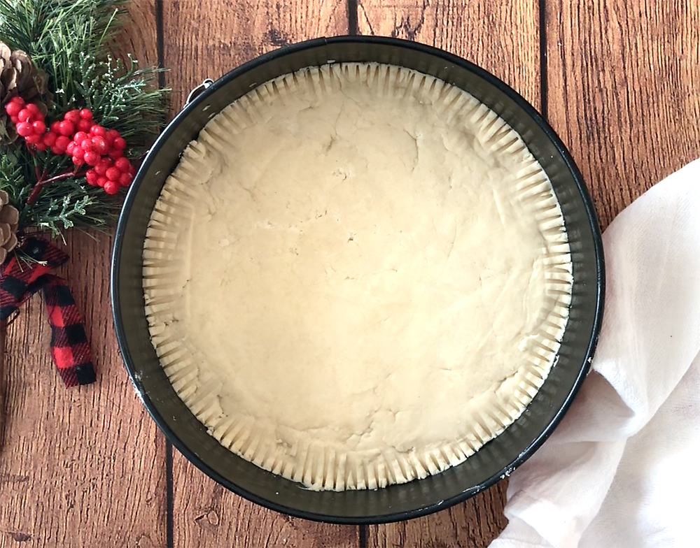 Shortbread dough pressed into the bottom of a springform pan, edges pressed with fork tines