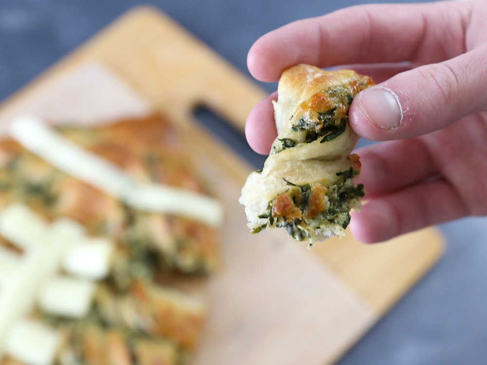 Hand holding piece of spinach dip breadstick