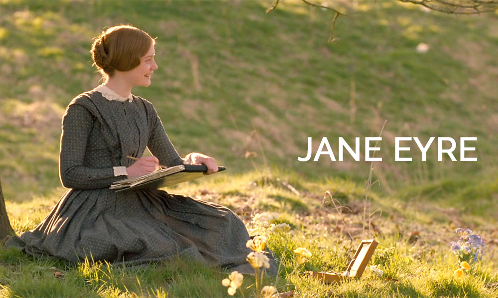 A young woman sitting on top of a grass covered field in the movie Jane Eyre