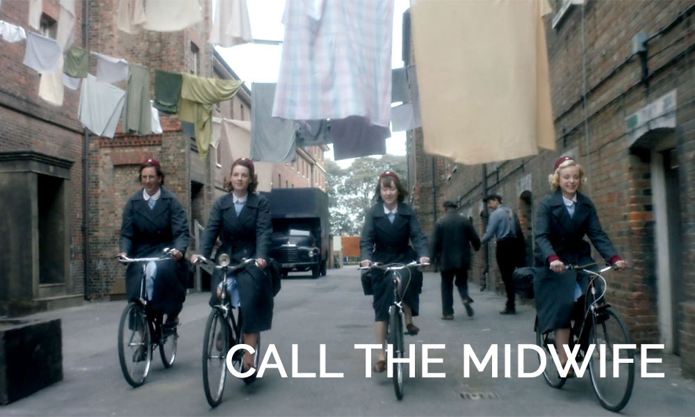 A person riding a bicycle on a city street in Call the Midwife