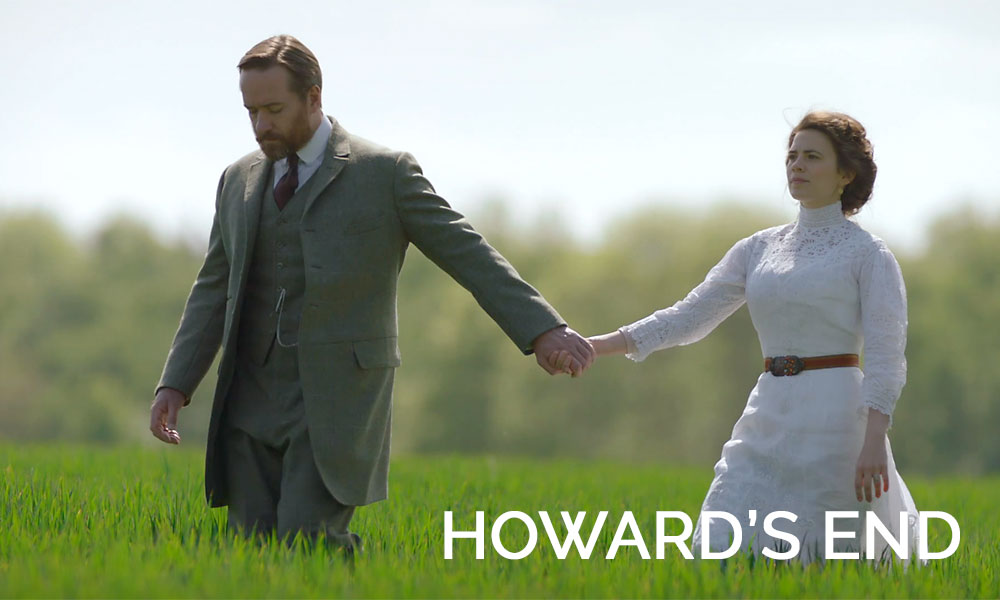 A man wearing a suit holding hands with a woman in a dress in the movie Howard\'s End