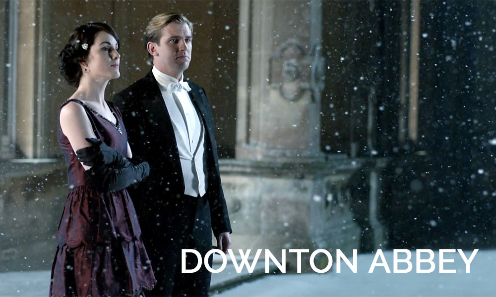 A woman standing in front of a building, with Downton Abbey