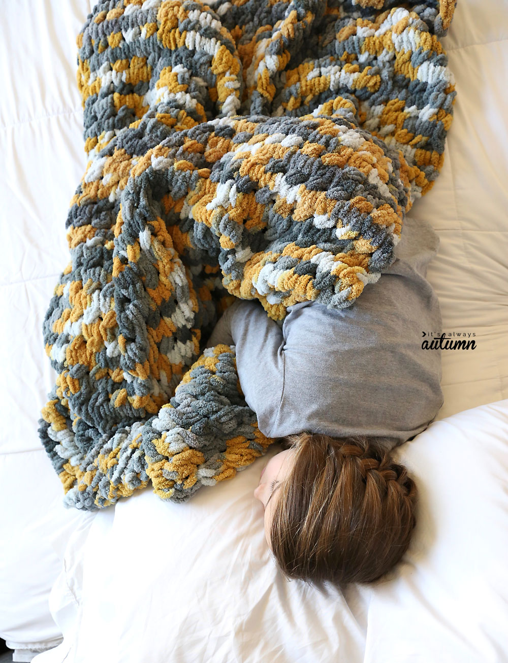 Girl curled up on a bed with a finger knit blanket