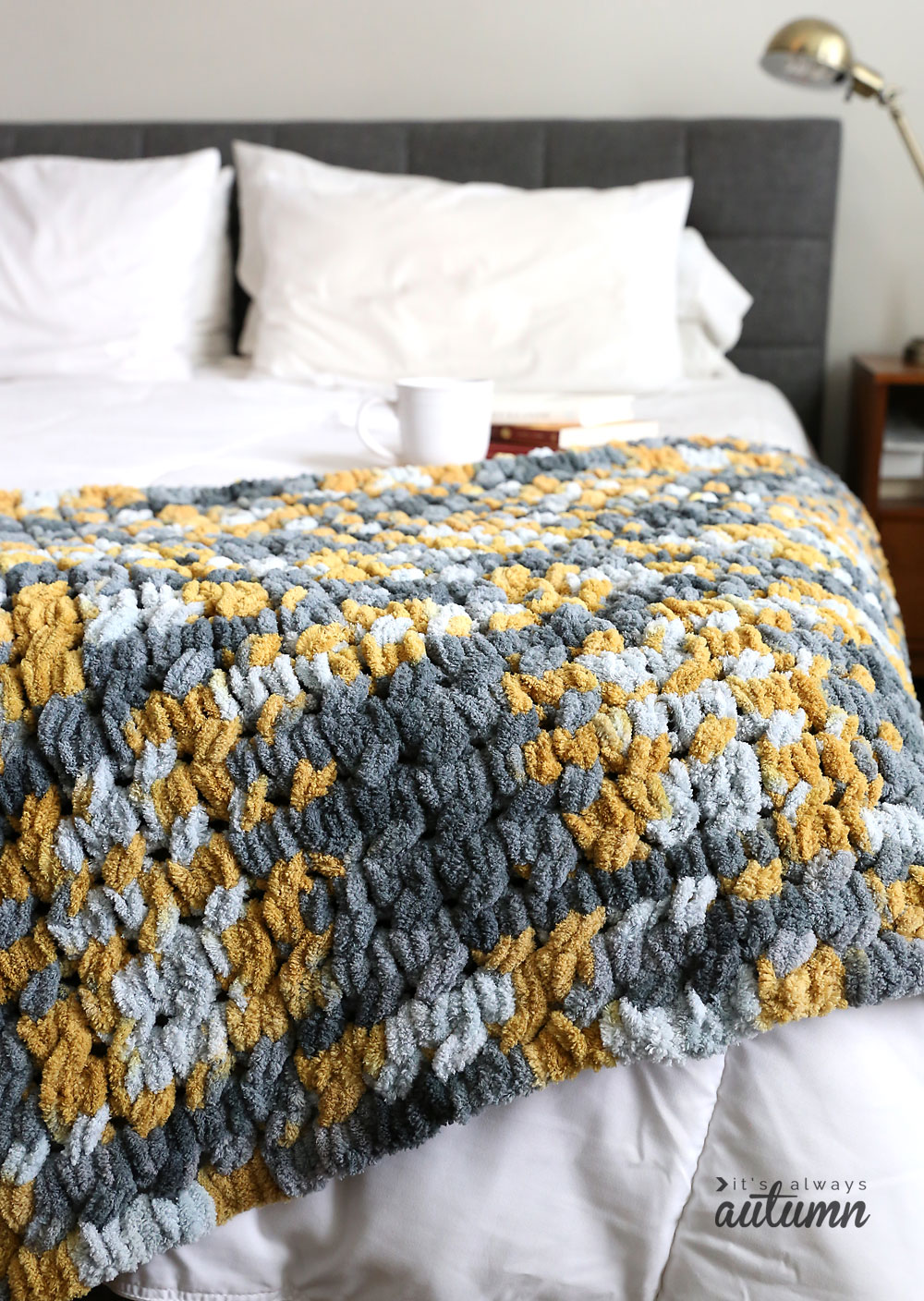 Grey and yellow cable knit blanket on a bed