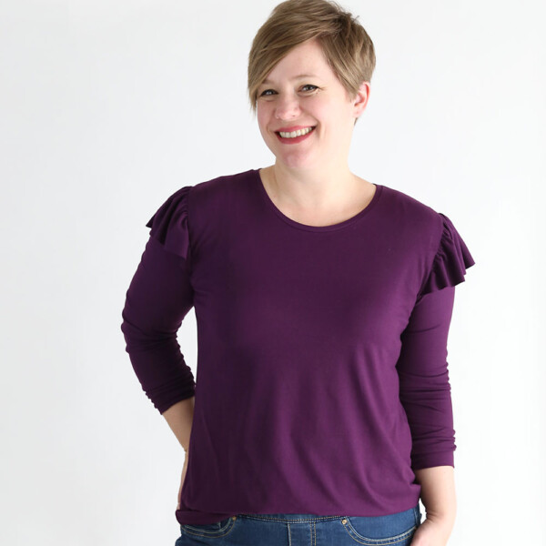 A woman wearing a purple long sleeve t-shirt with ruffles at the shoulders