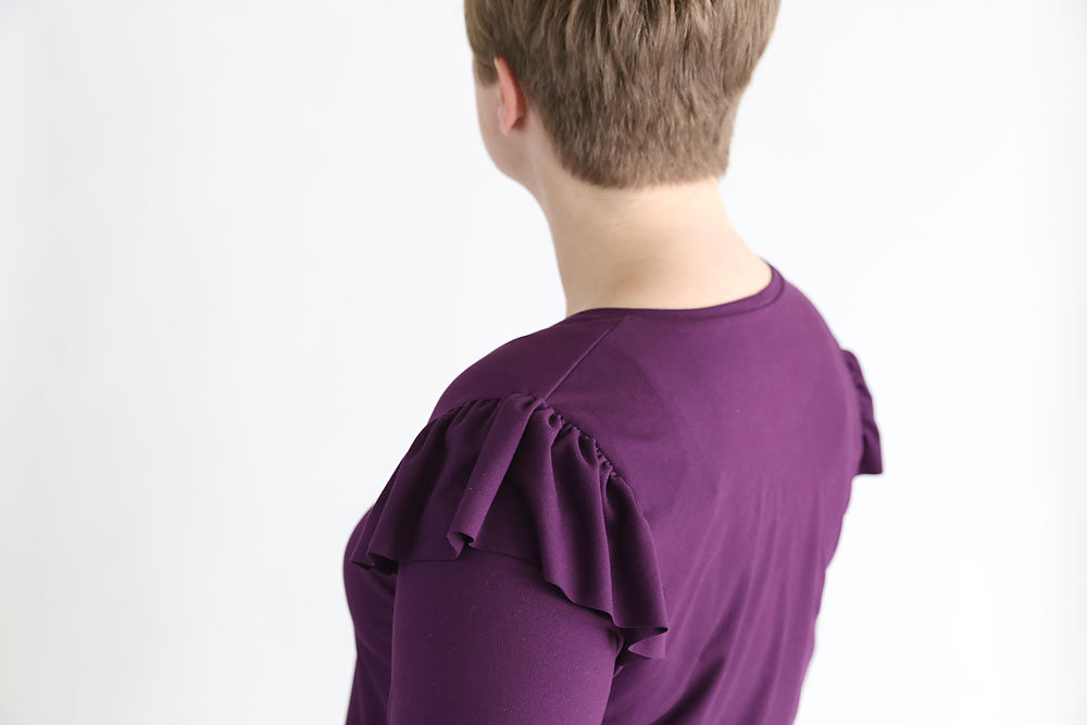 A closeup of shoulder ruffles on a purple t-shirt
