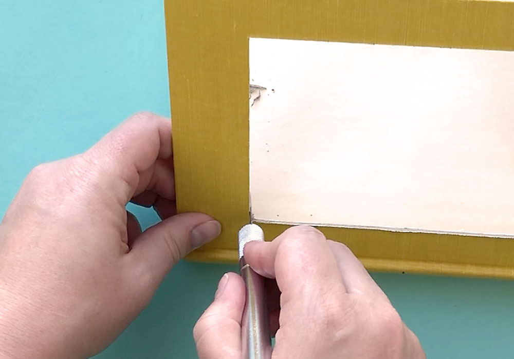 Hands using exacto knife to cut window from book cover