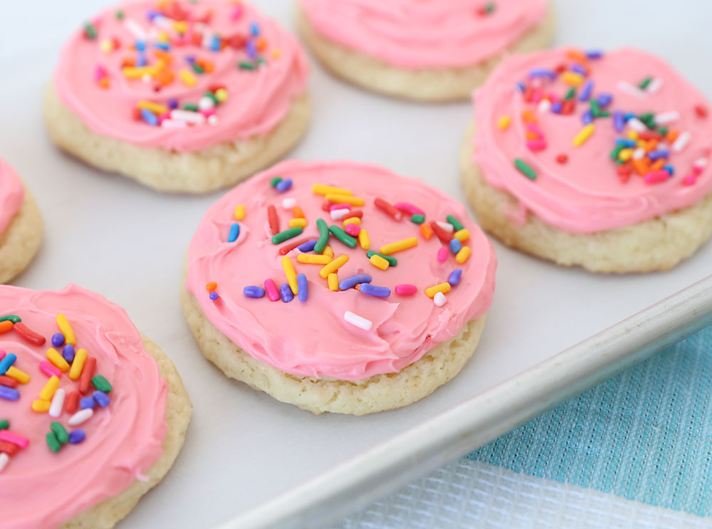 Sugar cookies made from a cake mix with pink frosting and sprinkles on a plate