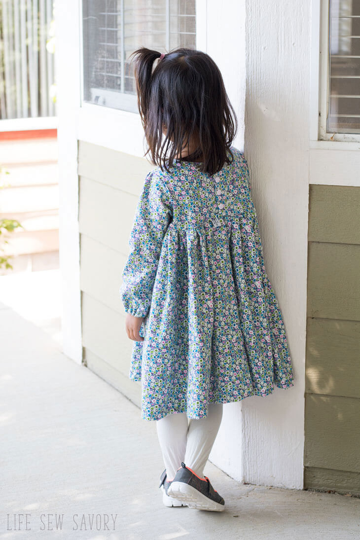 A girl in a long sleeve dress with buttons in the back