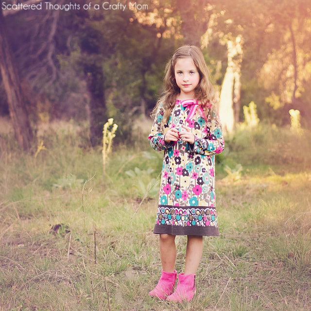 A little girl standing in a field wearing a long sleeve dress