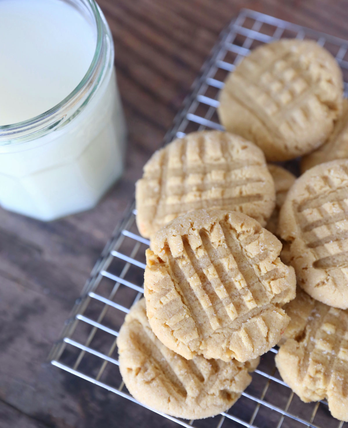 Peanut butter cookies on a cooling rack with a cup of milk